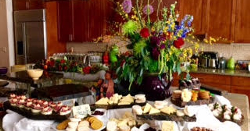 A room with a catering food table and floral display