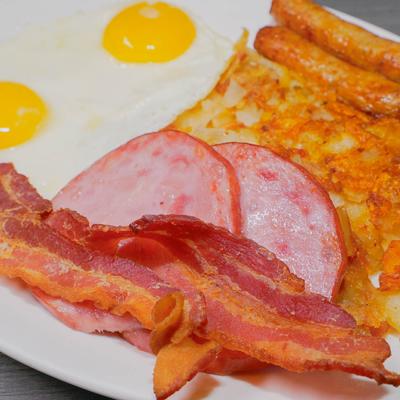 Sunny side up eggs, sausages, bacon, Canadian bacon, and hash browns.