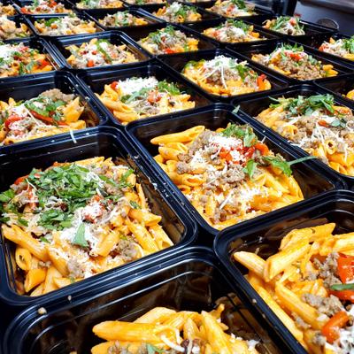 Numerus containers of prepared pasta meals topped with cheese and herbs.
