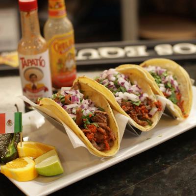 Tacos Locos plate on a bar counter with sauce bottles.