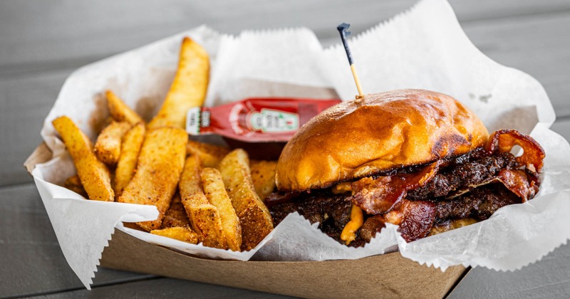 Double bacon cheeseburger accompanied by fries and a packet of ketchup