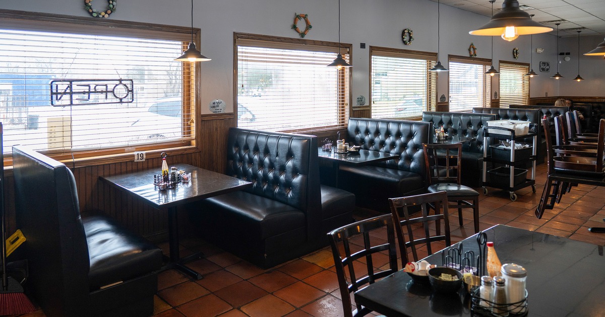 Cozy interior dining area with black upholstered dining booths lined up along the windows