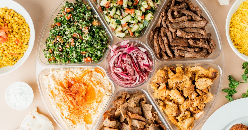 Catering platter with gyro meats, quinoa salad, hummus, and red onion