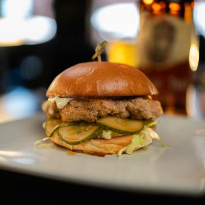 Fried chicken sandwich with pickles, lettuce, and mayo on a toasted bun.