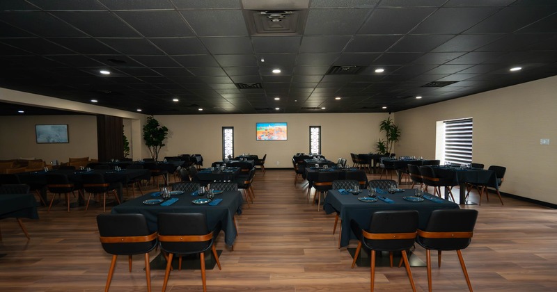 Spacious dining room with black ceiling, wooden floor, and tables set