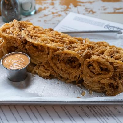 Onion ring loaf served with dipping sauce on a tray.