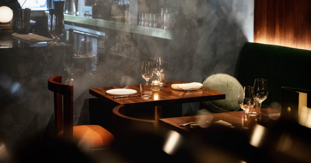 Romantic restaurant table setup with candlelight, wine glasses, and banquette seating