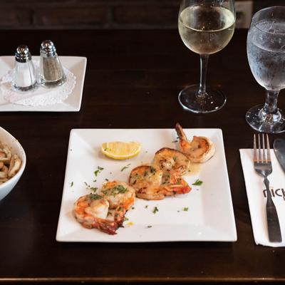 Shrimp, seasoned with herbs and served with lemon, accompanied with white wine.