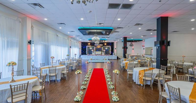 Interior, elegant event hall with a red carpet, chandeliers, and floral decorations
