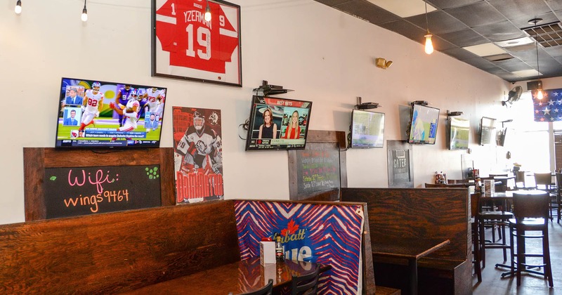 Interior, sitting booths, tv screens and framed jersey on the wall
