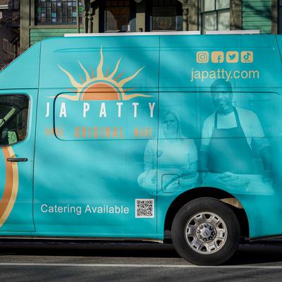 Turquoise food truck with the logo, social media handles, and a QR code.