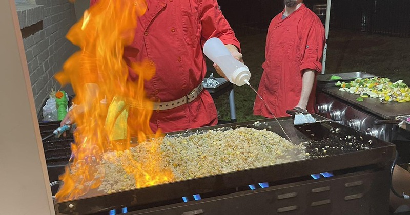 A chef preparing food on a large teppanyaki grill