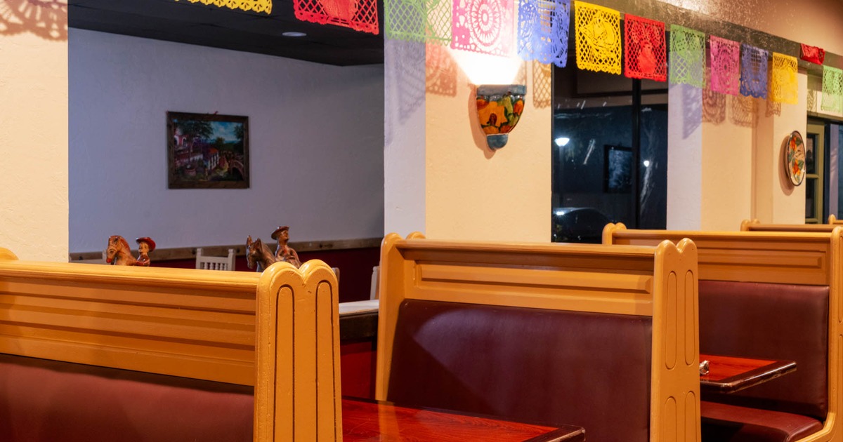 Restaurant interior with wooden booths and colorful papel picado banners