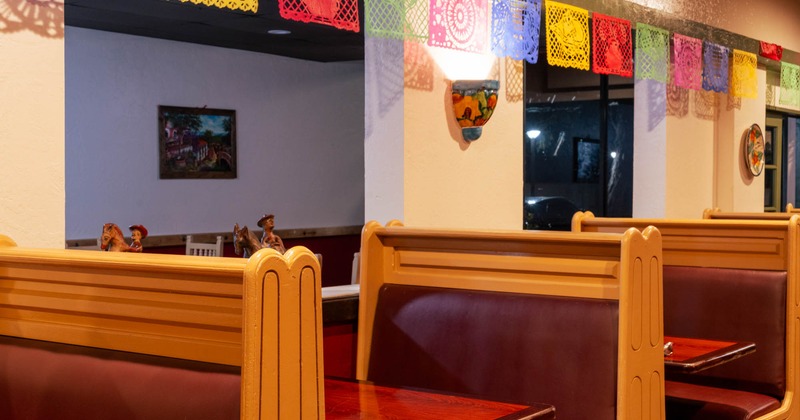 Restaurant interior with wooden booths and colorful papel picado banners