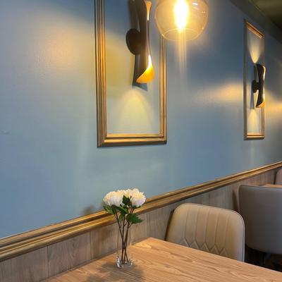 Blue wall dining area with framed lights and flowers.