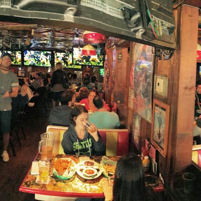 A lively sports bar scene with patrons eating and drinking at tables