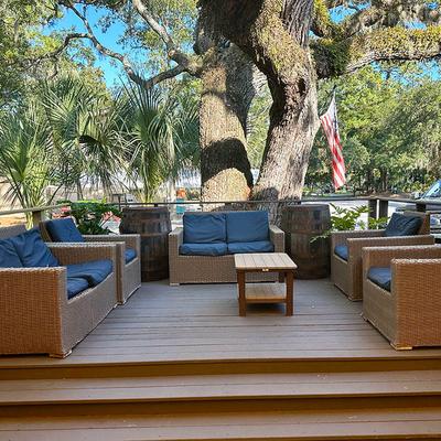 Outdoor deck with wicker furniture and a tree.