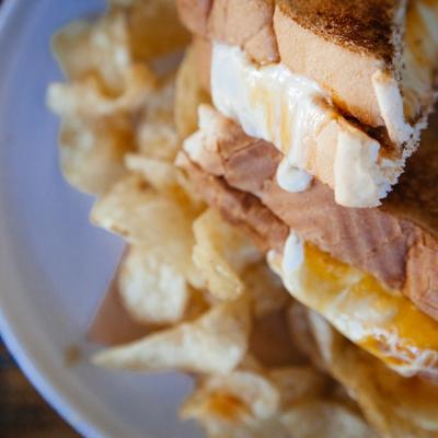 Grilled cheese sandwich with a side of chips.