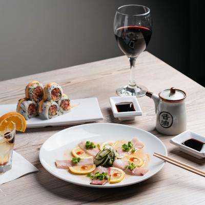 Hamachi jalapeno plate, Spicy Tuna and drinks on a table.