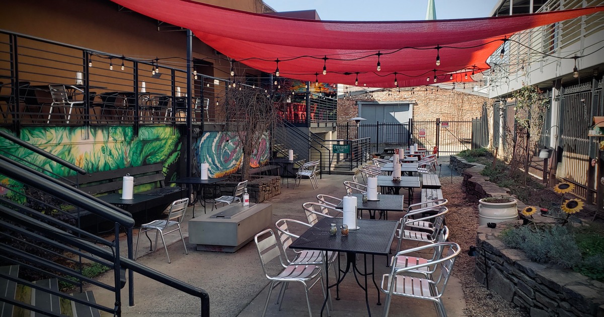 Seating area with tables and chairs, covered with sun shade sails