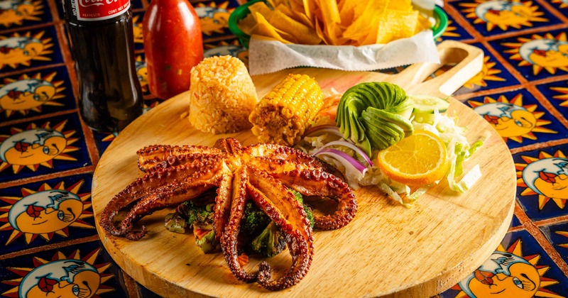 Grilled octopus served with rice, corn on a cob and a salad