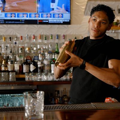 A bartender preparing a cocktail behind a bar counter.