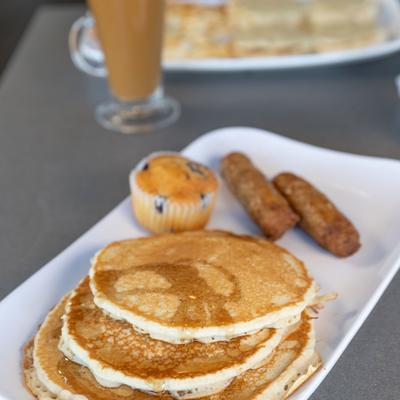Pancakes served with sausage links and a muffin.