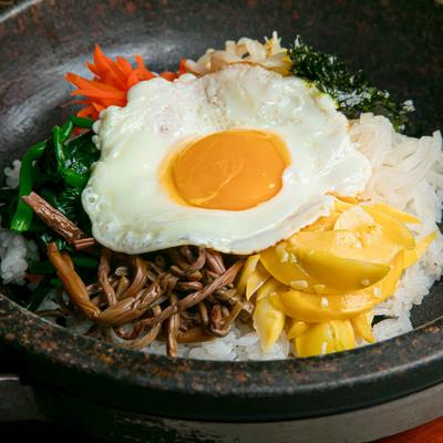 Thistle pot meal with noodles, rice, vegetables, and a sunny side up egg.