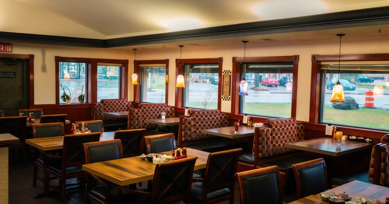 Interior, seating booths with tables, windows with rolled up blinds, regular tables and chairs