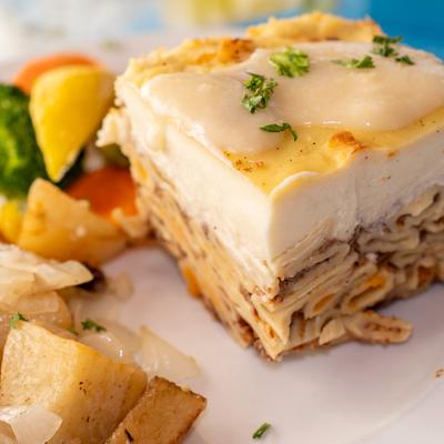 Layered macaroni and ground beef dish served with steamed vegetables and roasted potatoes.