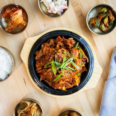 Korean spicy marinated pork with vegetable plate surrounded by various salads.