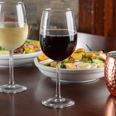 Glasses of red and white wine served with salad plates and a mule cocktail.