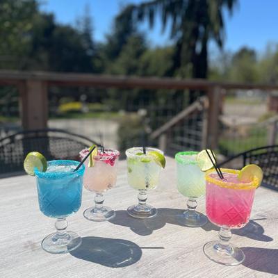 Various cocktails on a table outside in the sunlight.