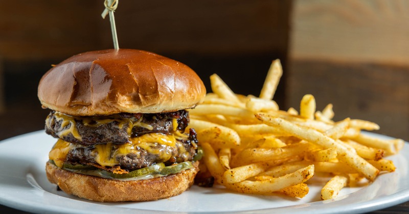 Cheeseburger served with seasoned fries on a white plate