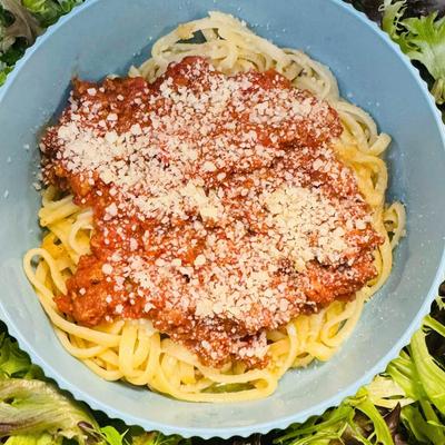 Spaghetti topped with tomato meat sauce and grated cheese.