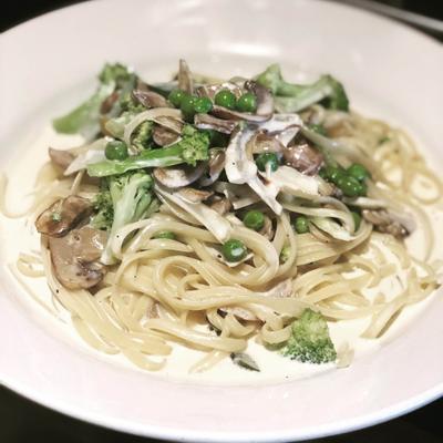 Pasta with creamy sauce, mushrooms, peas, and broccoli.