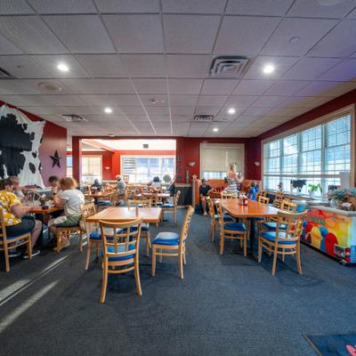 Indoor restaurant dining room with wooden tables, chairs, and acoustic tile ceiling.