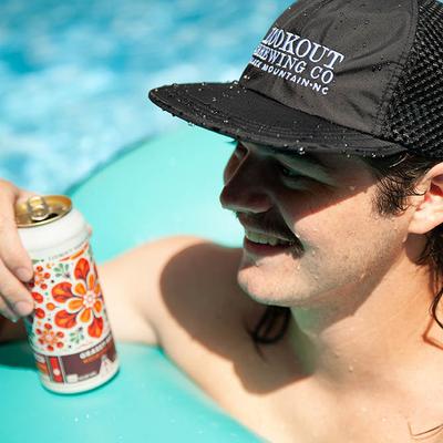 Person in a pool holding a can with floral design.