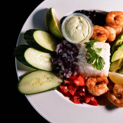 Jasmine rice bowl with shrimp, diced red onion, cucumber, and avocado.
