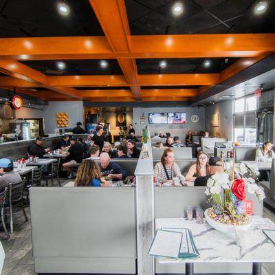 People dining in a busy restaurant with booth seating.