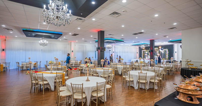 Inside, banquet hall, decorated round tables, white cloths, floral centerpieces, crystal chandeliers