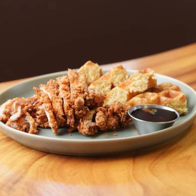 Garlic chicken and waffles served with syrup on the side.