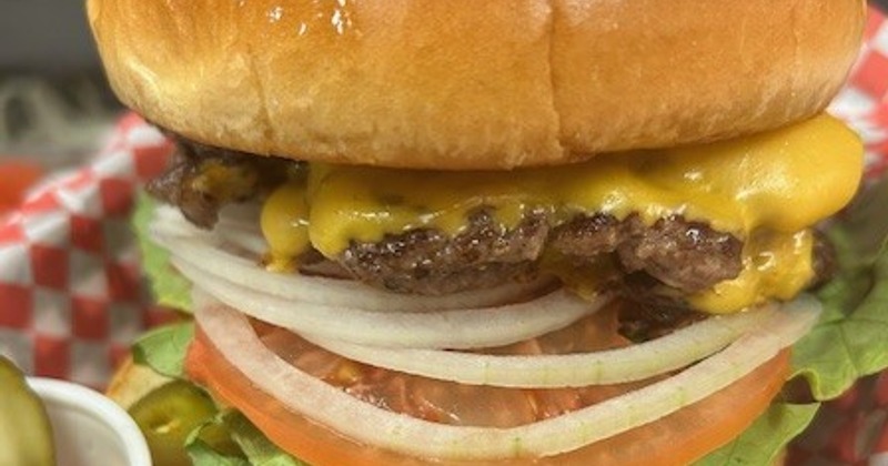 Close-up of a cheeseburger with tomato, onion, and lettuce