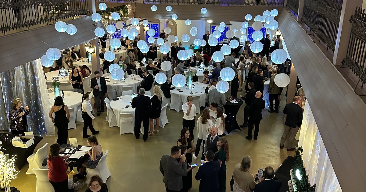 Indoor catering event in a large ballroom with balconies and hanging lights