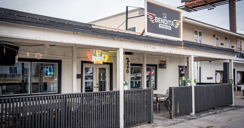 Exterior, angle view to front of restaurant, porch terrace, tables, chirs, entrance, sign above