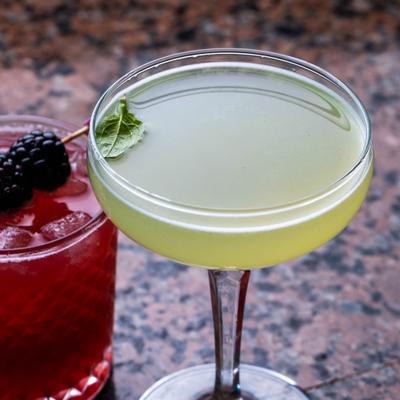 Two cocktails on granite countertop, green and red.