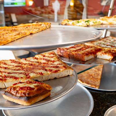 Stands with different types of pizza inside a display case.