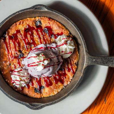 Skillet dessert with ice cream and berry sauce drizzle.