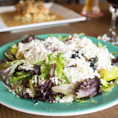 Greek Salad topped with grated cheese, close view.