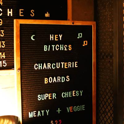 A dark board listing various charcuterie boards, including cheesy and meaty options.